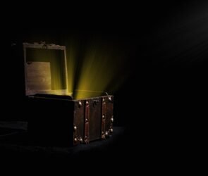 Person opening a mystery box filled with assorted collectibles, gadgets, and surprise items on a table.