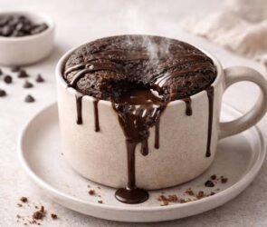 Freshly made chocolate lava mug cake with a warm molten chocolate center, topped with vanilla ice cream and chocolate shavings.