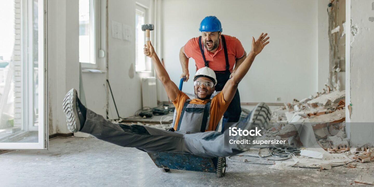 Construction workers laughing together during a break while sharing funny construction jokes on a busy job site.