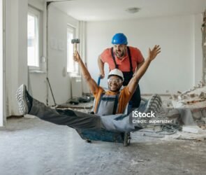 Construction workers laughing together during a break while sharing funny construction jokes on a busy job site.