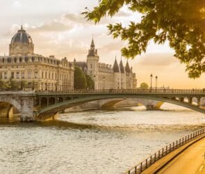 Panoramic view of Paris featuring the Eiffel Tower, the Seine River, and historic landmarks on a sunny day