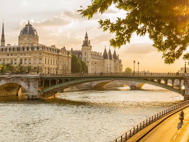 Panoramic view of Paris featuring the Eiffel Tower, the Seine River, and historic landmarks on a sunny day