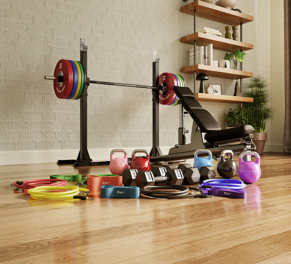 "Small gym equipment including adjustable dumbbells, resistance bands, kettlebell, yoga mat, jump rope, and foam roller arranged in a compact home gym."